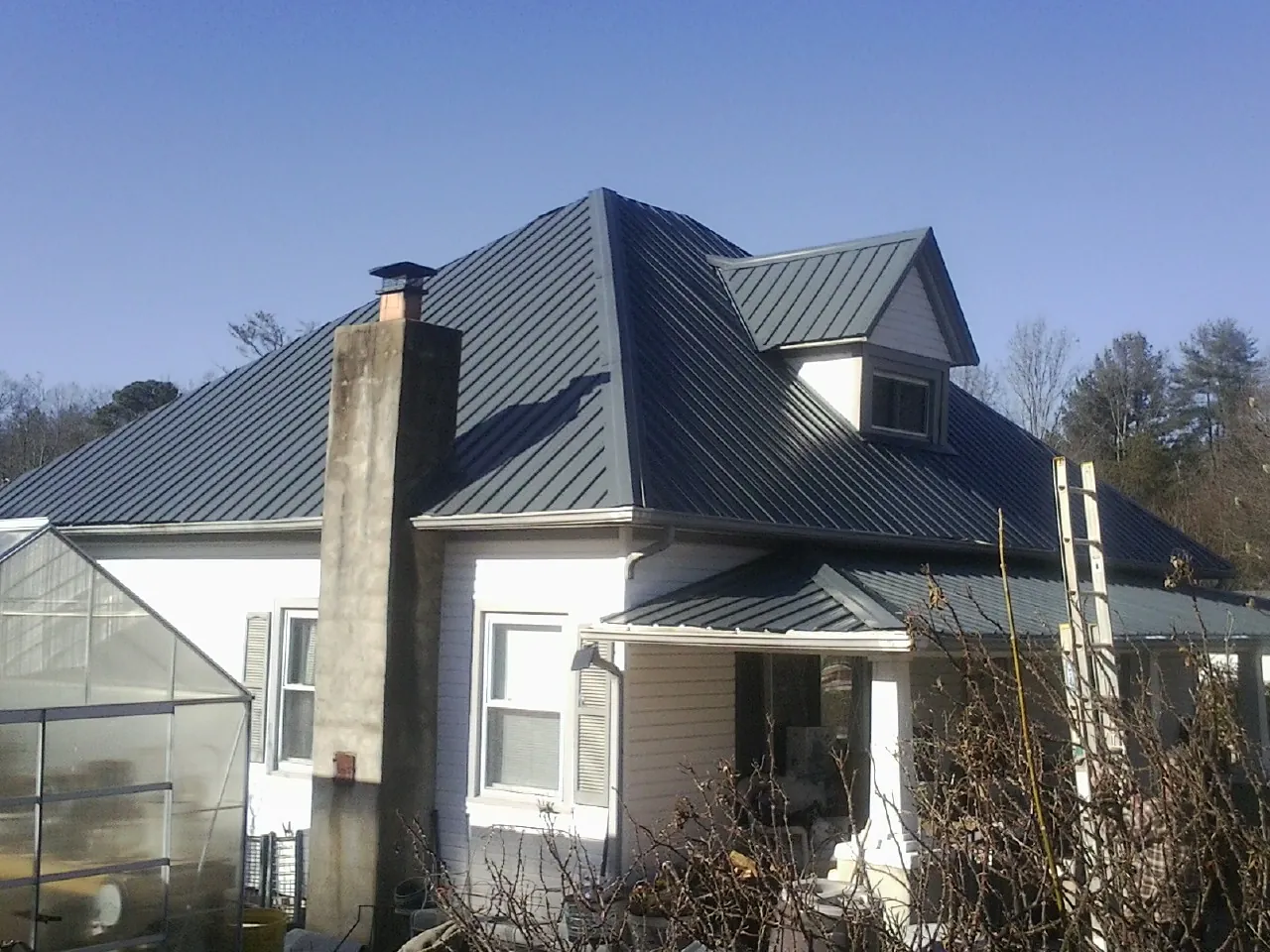 Dark blue standing seam metal roof on a white farmhouse with dormer — Slate & Tile Roof Repair by Roofing Brothers in Wilkesville