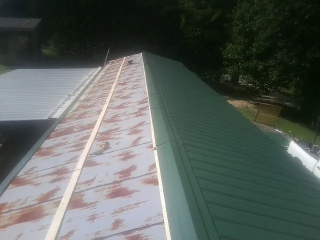 Old rusted panels beside newly installed green metal roofing — Wind Damage Roof Repair by Roofing Brothers in Wilkesville