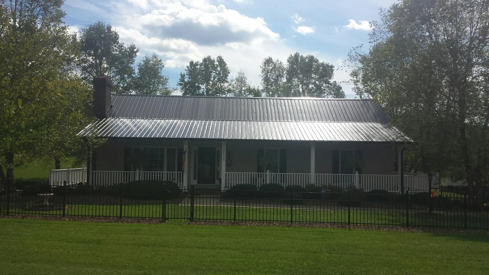Gray metal roof on a brick ranch with a full width front porch — Gutter Guard Installation work by our crew in Wilkesville