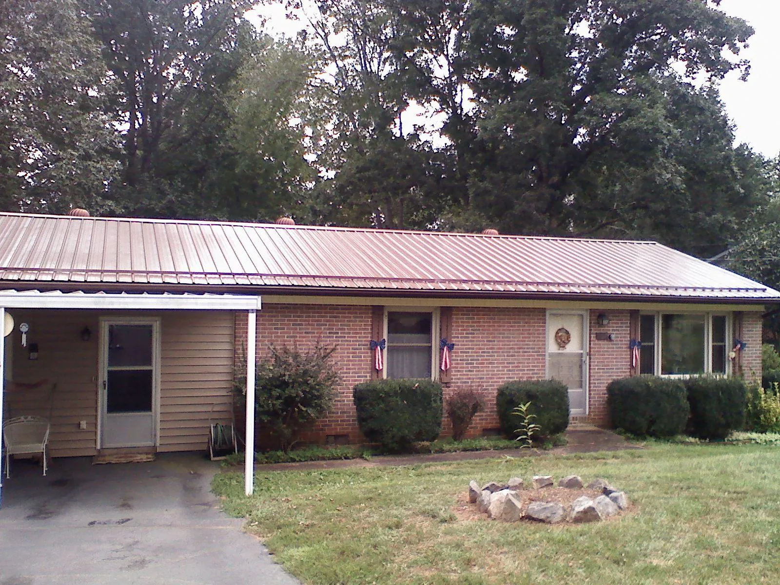 Bronze metal roof and carport on a brick ranch home — Roof Repair work by our crew in Wilkesville