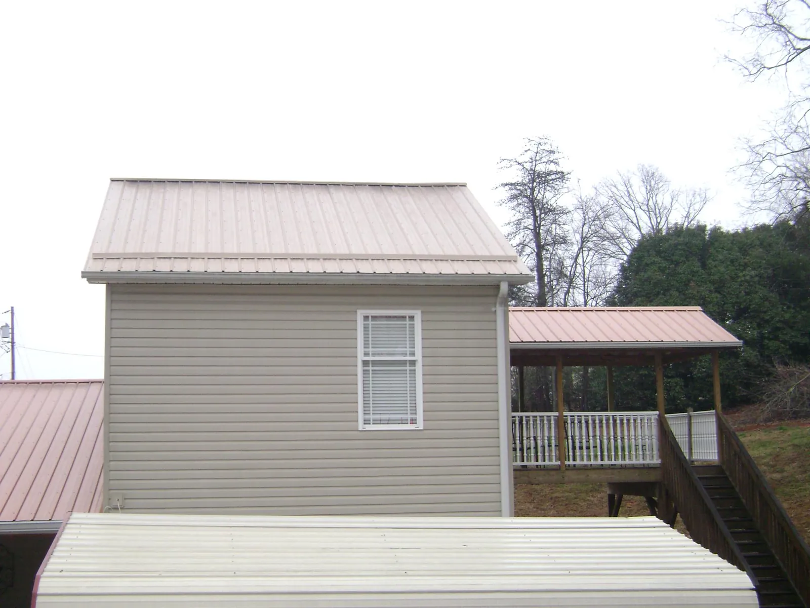Tan metal roofs on a two story addition and attached porch, from a Roof Replacement job in Wilkesville