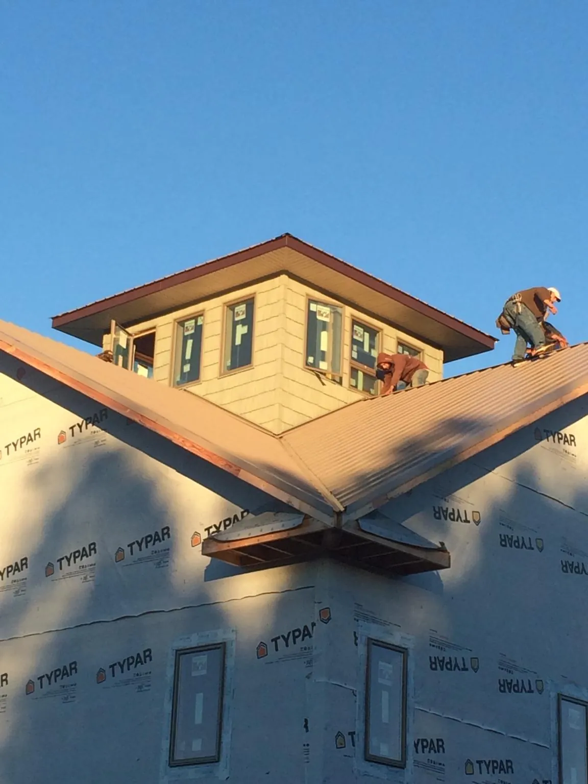Roofers working around a rooftop cupola on a new metal roof at sunset — Roof Waterproofing in Wilkesville by Roofing Brothers